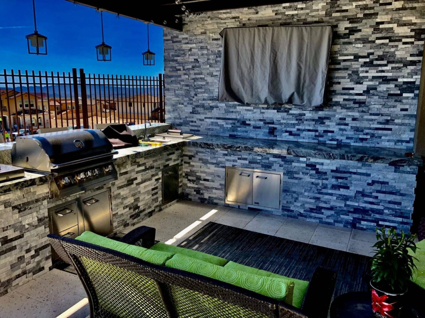 A patio with an outdoor grill and a stone wall.