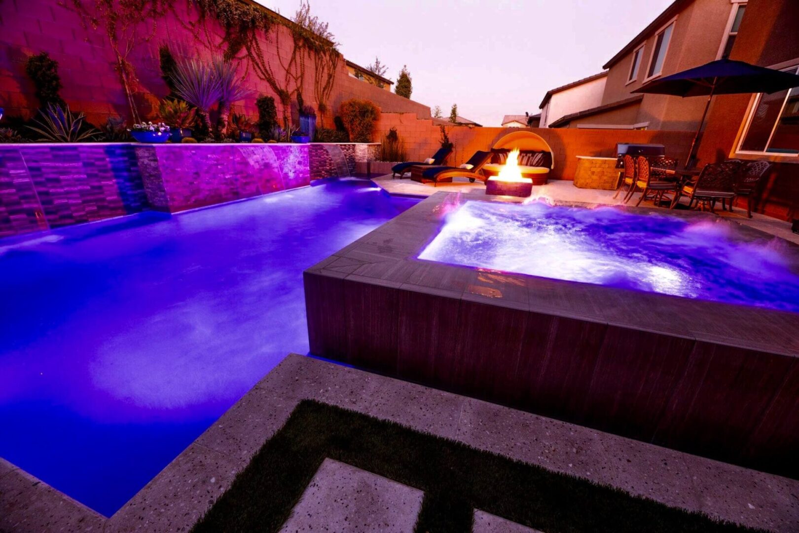 A pool with a fire pit and jacuzzi in it