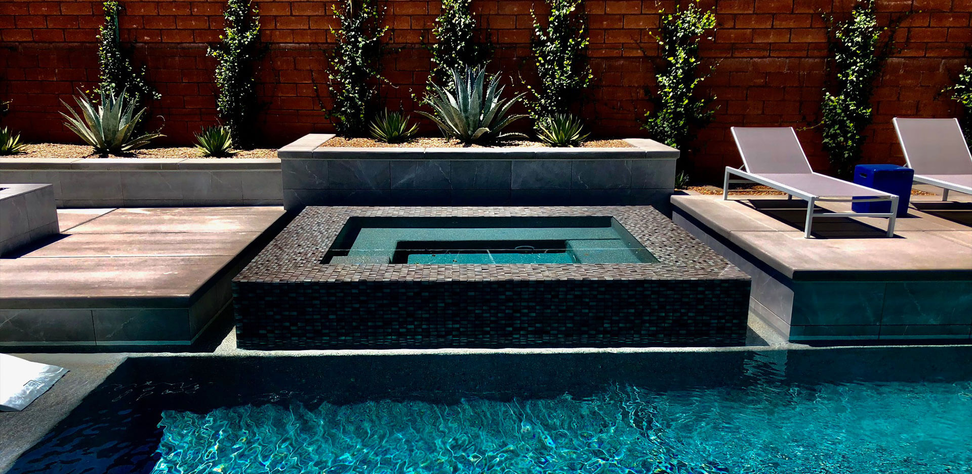 A pool with a stone bench and water feature.