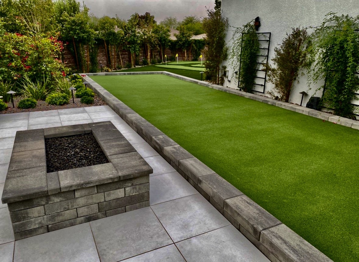 A backyard with a fire pit and grass.