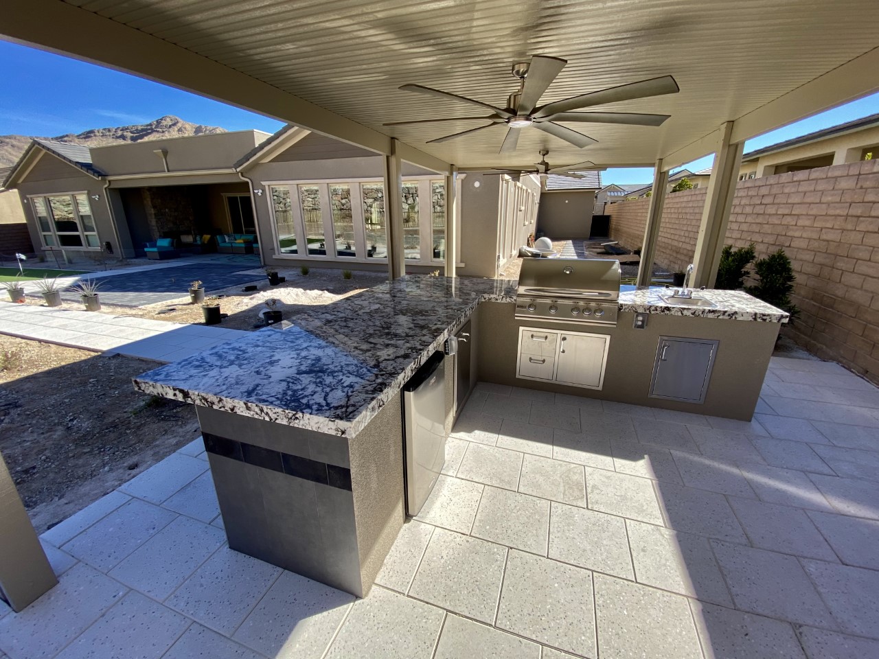 A large outdoor kitchen with an overhead fan.