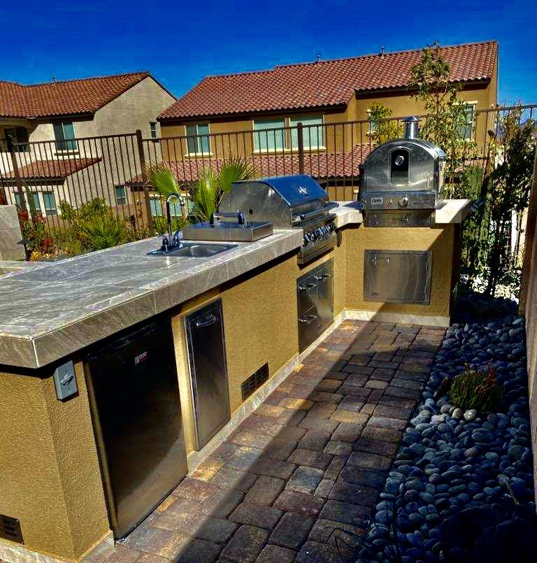 A large outdoor kitchen with a sink and grill.