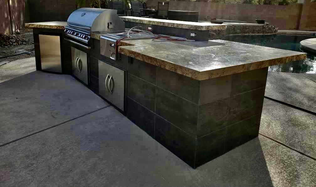 A grill and an outdoor kitchen with concrete countertops.