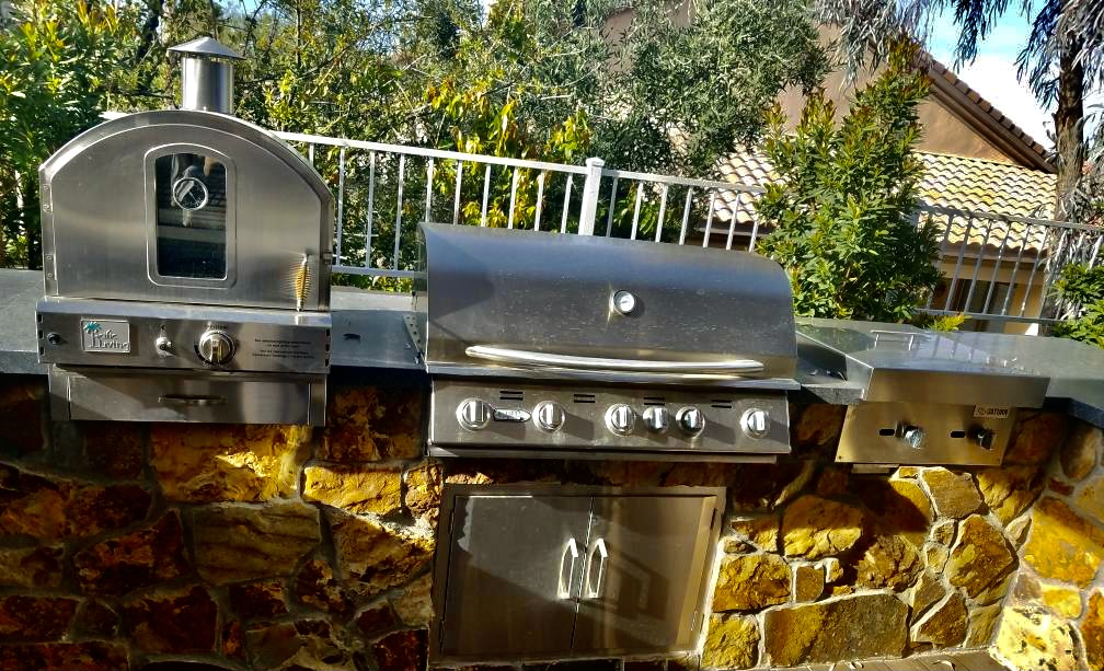 A grill sitting on top of a stone wall.
