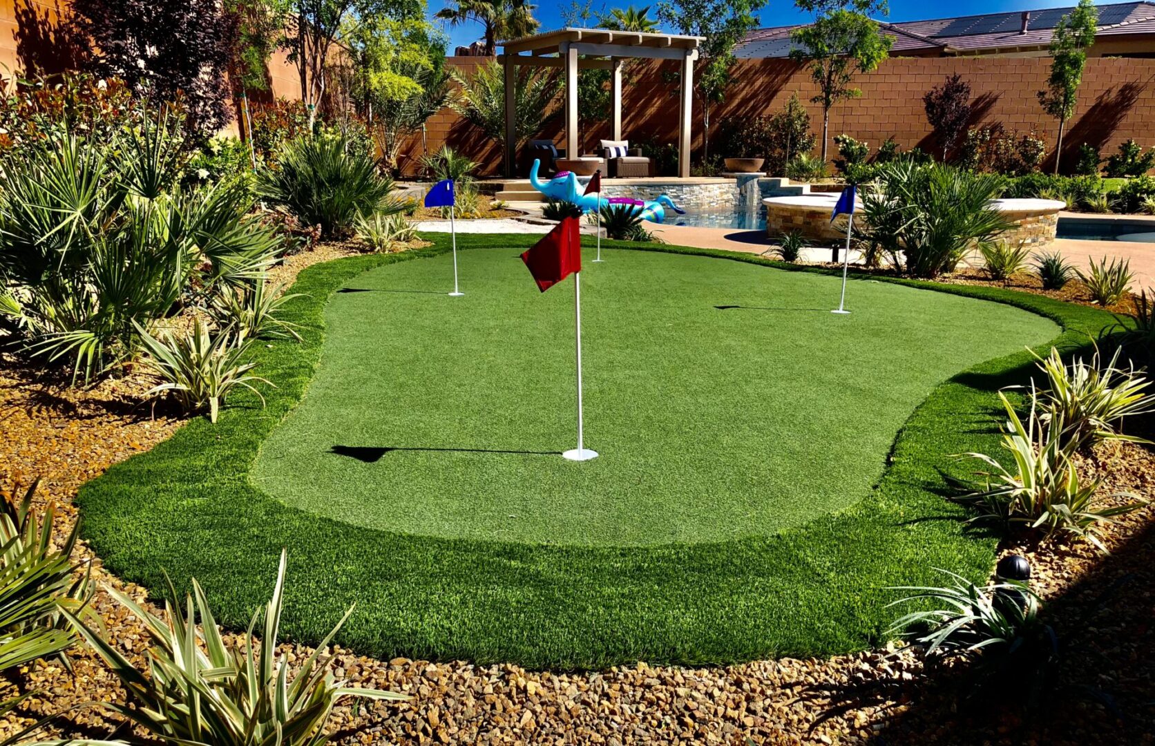 A backyard with a putting green and pool.