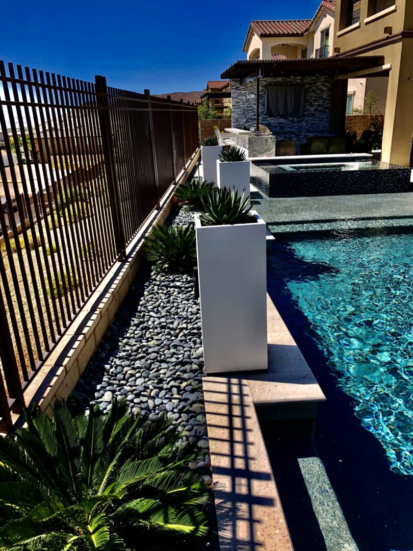 A pool with a stone wall and a fence.