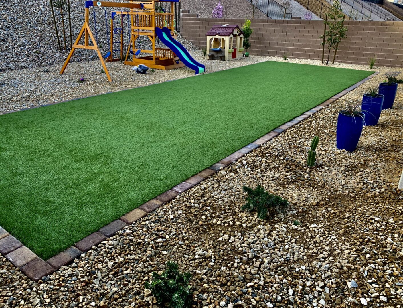 A backyard with a slide, sandpit and grass.