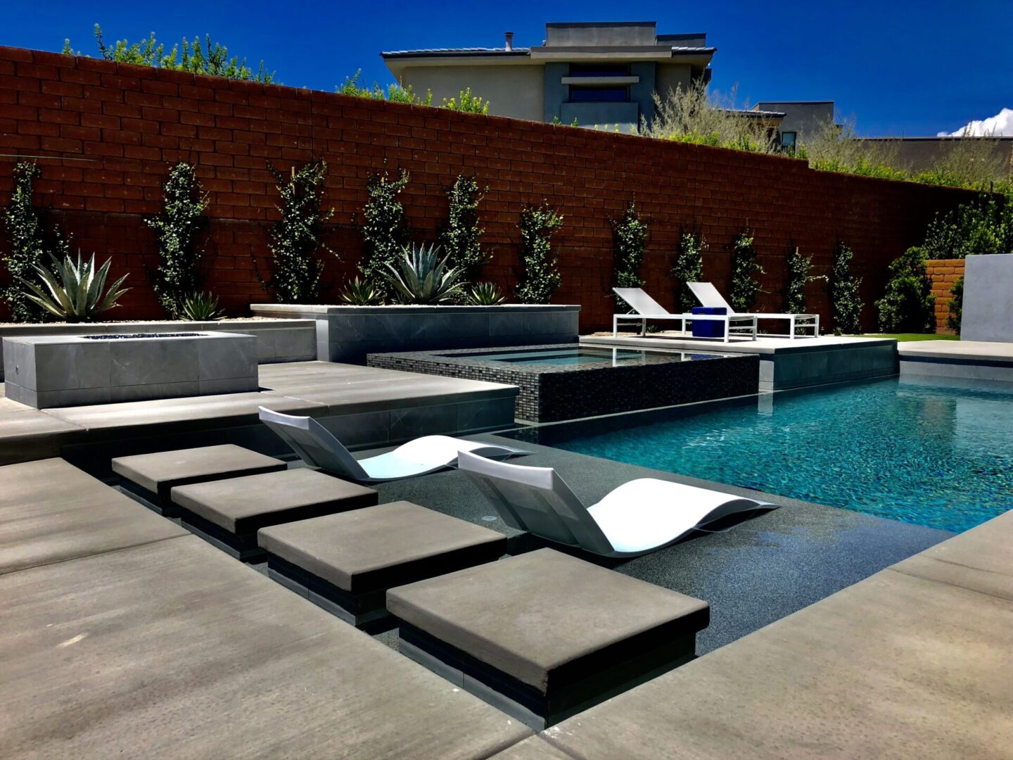A pool with lounge chairs and a bench.