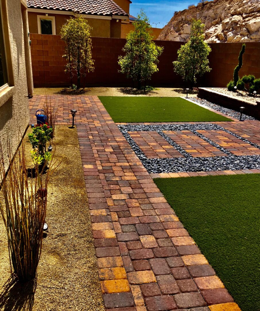 A brick walkway with grass and plants in the middle.