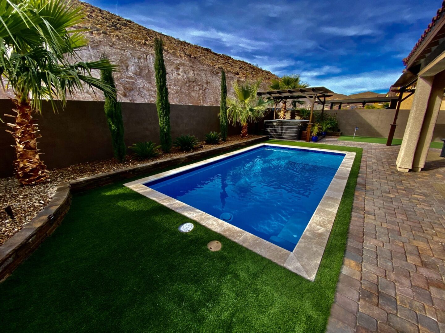 A pool with grass and palm trees in the background.