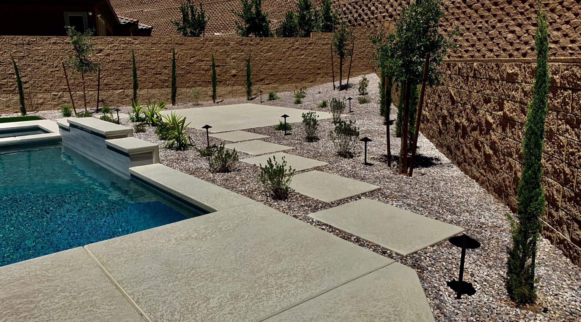A pool area with a stone wall and gravel.