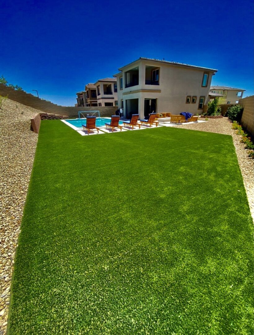 A backyard with pool and grass on the ground.