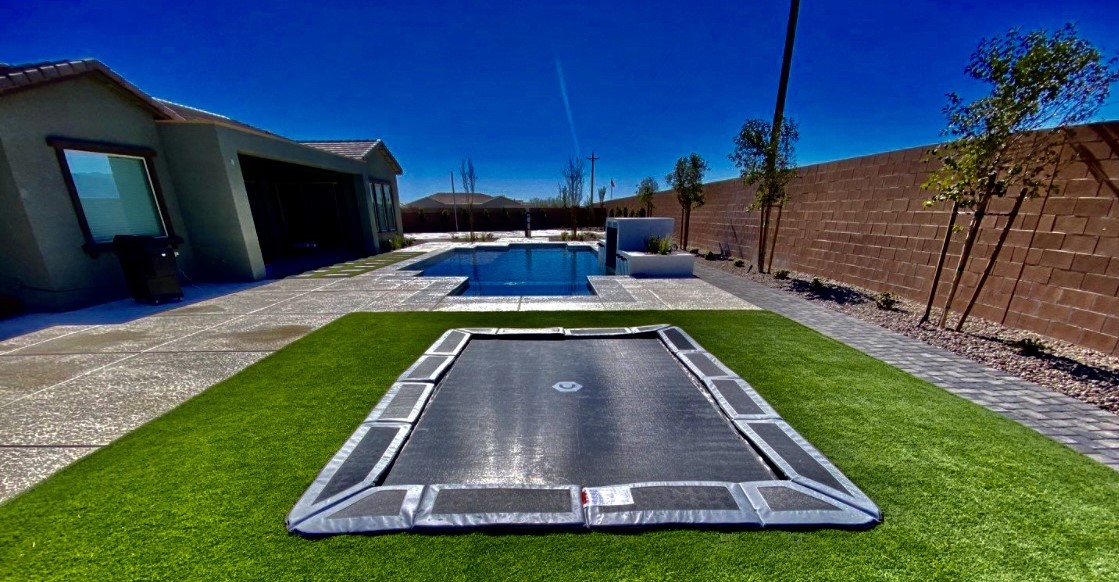 A trampoline in the middle of an artificial grass area.