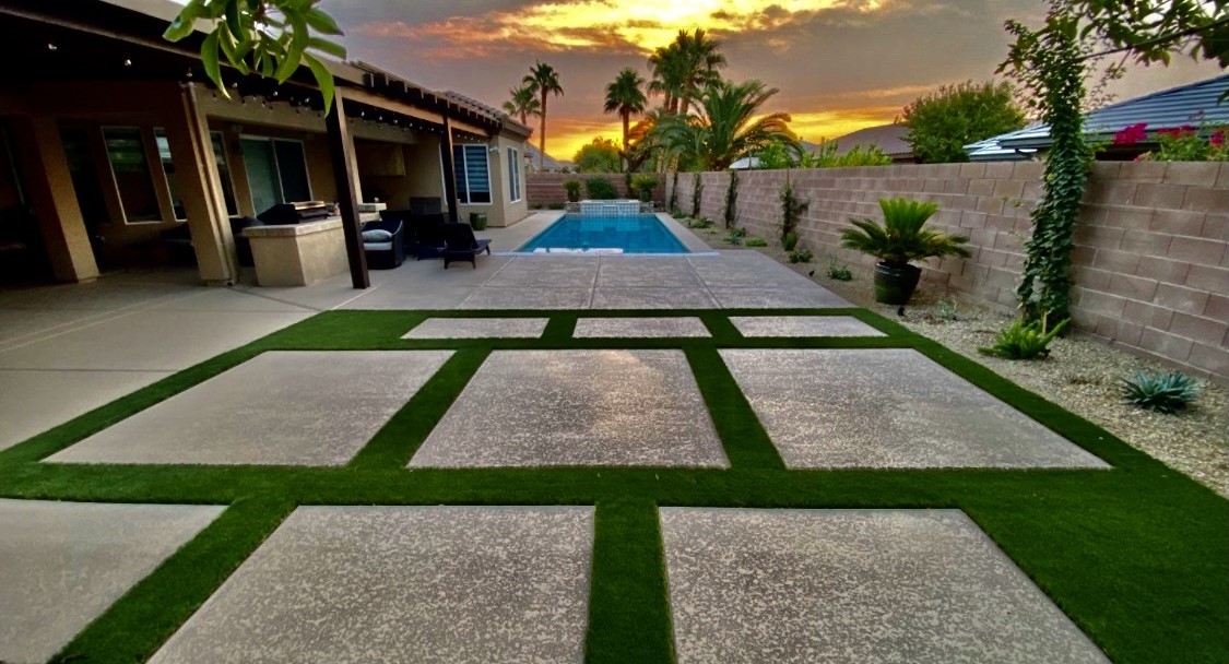 A pool with grass on the ground and a patio