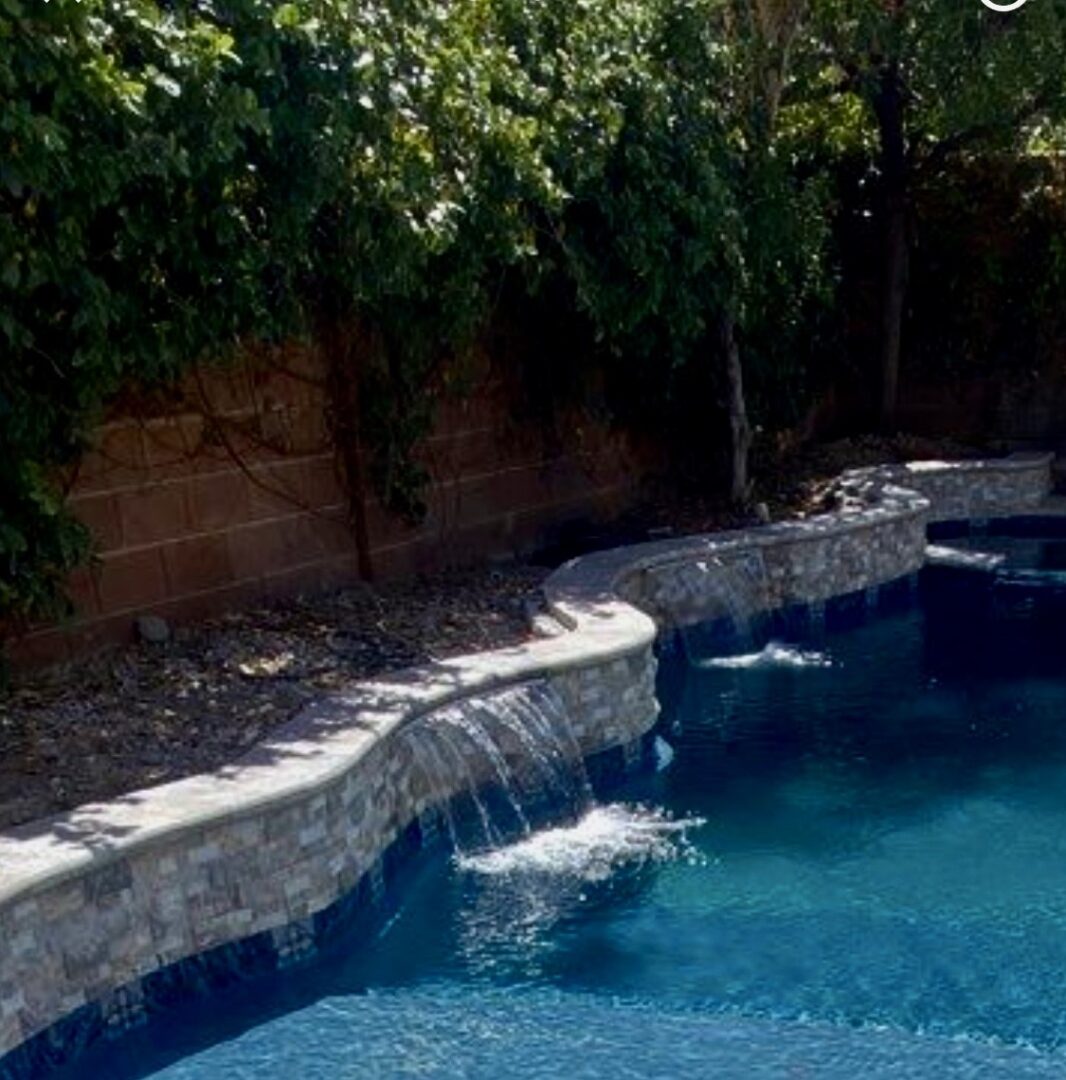 A pool with water falling down the side of it.