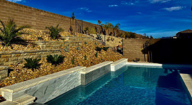 A pool with a stone wall and steps leading to it.