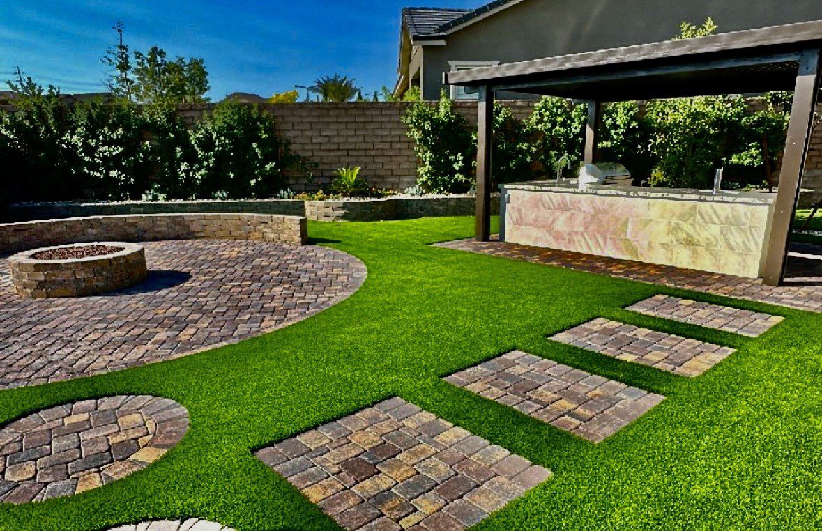 A backyard with grass and brick pavers