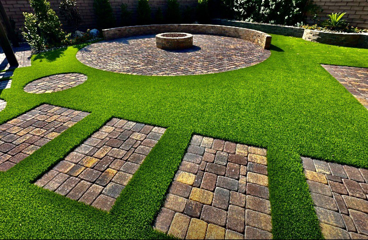 A backyard with grass and brick pavers