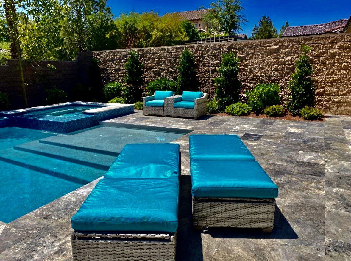A pool with blue furniture and a stone wall.